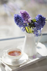 Heißer Tee in einer alten Tasse mit Blumenvase zu Hause - ONAF00167