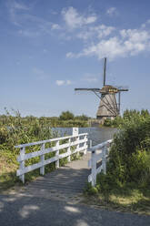 Niederlande, Südholland, Kinderdijk, Uferpromenade mit historischer Windmühle im Hintergrund - KEBF02406