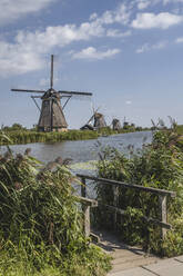 Niederlande, Südholland, Kinderdijk, Uferpromenade mit historischen Windmühlen im Hintergrund - KEBF02408