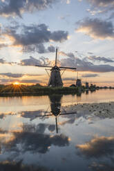 Niederlande, Südholland, Kinderdijk, Fluss auf dem Lande und historische Windmühlen bei Sonnenuntergang - KEBF02413