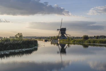 Niederlande, Südholland, Kinderdijk, Ländlicher Fluss und historische Windmühlen in der Abenddämmerung - KEBF02416