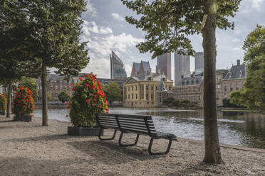 Niederlande, Südholland, Den Haag, Parkbank vor dem Hofvijver Seekanal mit dem Mauritshuis Museum im Hintergrund - KEBF02428