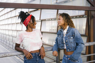 Multiracial young women talking near railing - MMPF00351