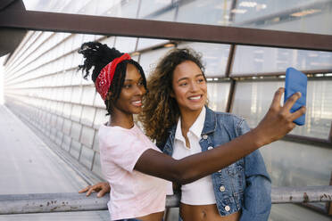 Lächelnde multirassische Freunde, die ein Selfie mit einem Smartphone machen - MMPF00352