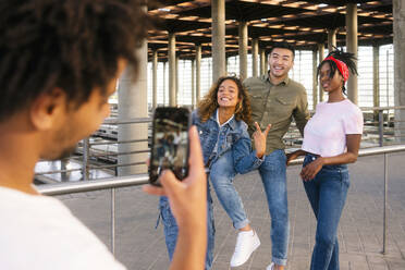 Junger Mann fotografiert seine Freunde mit dem Smartphone am Bahnhof - MMPF00360