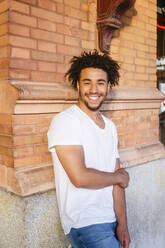 Smiling young man leaning on wall - MMPF00392