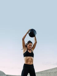 Fitte Frau mit Medizinball beim Training im Freien. Frau mit muskulösem Körper beim Training mit Fitnessball. - JLPSF07371