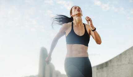 Athletic woman running outdoors in morning. Female in sportswear on a morning run. - JLPSF07378