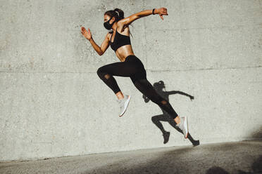 Fitness woman wearing face mask running outdoors. Woman athlete exercising outdoors in morning. - JLPSF07397