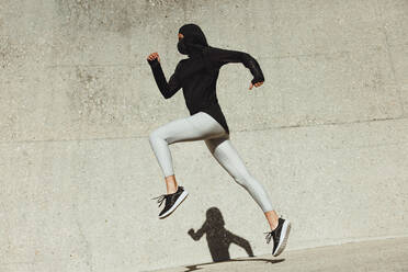 Frau in Sportkleidung beim Training im Freien. Frau läuft und springt in Sportkleidung. - JLPSF07436