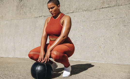 Gesunde Frau trainiert mit Medizinball. Plus size Frau in Sportkleidung mit Medizinball. - JLPSF07444