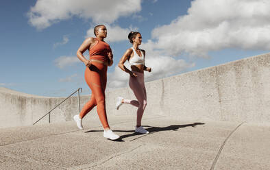 Zwei Frauen joggen zusammen. Freundinnen in Sportkleidung laufen am Morgen. - JLPSF07459