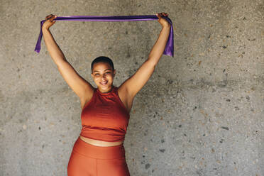 Healthy and fit woman exercising with resistance band. Oversized female in sportswear exercising outdoors. - JLPSF07471