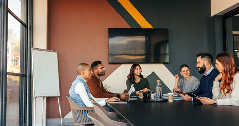 Eine Gruppe multikultureller Geschäftsleute bei einer Besprechung in einem Sitzungssaal. Zufriedene Geschäftsleute bei einer Diskussion während ihrer morgendlichen Besprechung. Junge Unternehmer bei der Zusammenarbeit in einem modernen Büro. - JLPSF07512