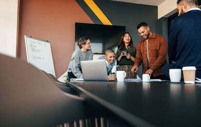 Erfolgreiche Geschäftsleute, die in einem Sitzungssaal einige Berichte besprechen. Eine Gruppe multikultureller Geschäftsleute, die in einem modernen Büro um einen Tisch herumstehen. Unterschiedliche Unternehmer, die an einem Projekt zusammenarbeiten. - JLPSF07522