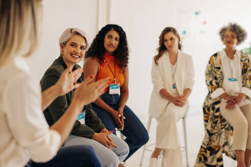 Zufriedene Geschäftsfrauen bei einer Diskussion während einer Konferenz an einem modernen Arbeitsplatz. Gruppe multikultureller Geschäftsfrauen, die in einem rein weiblichen Startup-Unternehmen zusammenarbeiten. - JLPSF07567