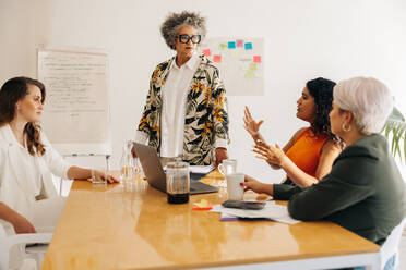Eine Gruppe unterschiedlicher Geschäftsfrauen diskutiert während einer Sitzung. Unternehmerinnen tauschen in einem Sitzungssaal kreative Ideen aus. Multikulturelle Geschäftsfrauen arbeiten in einem reinen Frauen-Startup zusammen. - JLPSF07600