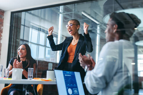 Employee of the month. Cheerful young businesswoman smiling while being applauded by her colleagues in a modern office. Happy young businesswoman receiving praise from her team during a meeting. - JLPSF07642