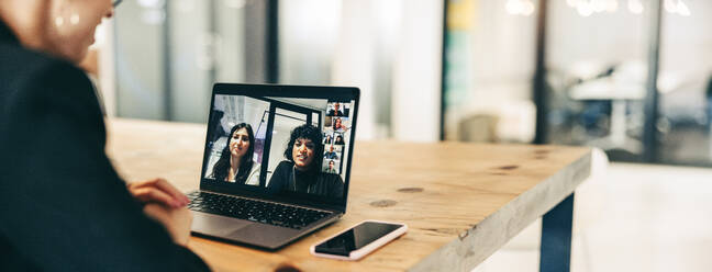 Junge Geschäftsfrau, die an einem virtuellen Meeting in einem modernen Büro teilnimmt. Selbstbewusste junge Geschäftsfrau, die einen Laptop für eine Videokonferenz mit ihren Partnern benutzt. Unternehmerin, die weltweit Geschäfte macht. - JLPSF07701