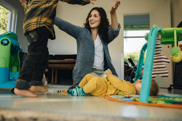 Mother playing with her two kids at home. Woman on maternity leave spending time with her children indoors. - JLPSF07867