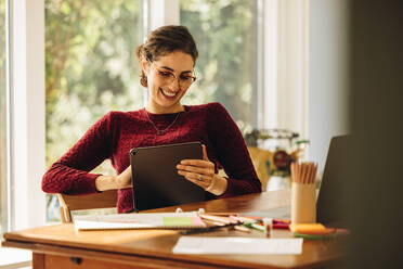 Frau Illustratorin sitzt zu Hause und lächelt mit einem digitalen Tablet. Weibliche Designer arbeiten zu Hause mit Tablet-PC. - JLPSF07899
