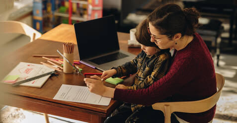 Kid using digital tablet while sitting on lap of his mother. Woman with son drawing in graphic table using stylus pen. - JLPSF07906