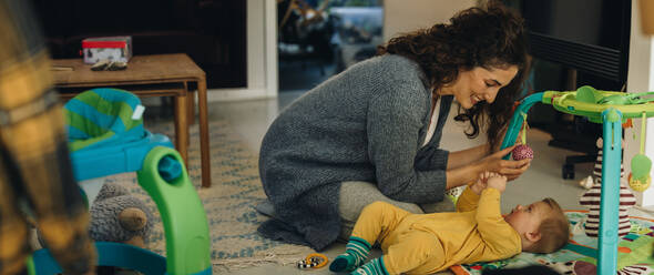 Frau spielt mit ihrem Kind, das zu Hause auf dem Boden liegt. Mutter und Sohn spielen zu Hause. - JLPSF07914