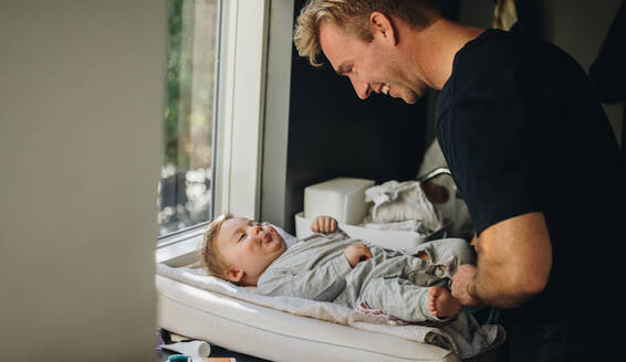 Caring father changing diaper of his baby. Man on paternity leave taking care of his baby. - JLPSF07919