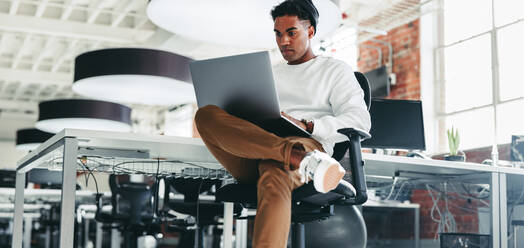 Programmierer, der an einem neuen Projekt in einem Büro arbeitet. Konzentrierter junger Geschäftsmann, der einen Laptop benutzt, während er an einem modernen Arbeitsplatz sitzt. Kreativer Geschäftsmann, der tagsüber alleine arbeitet. - JLPSF07941