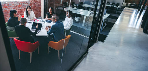 Weibliche Vorgesetzte, die ihr Team in einem Büro instruiert. Selbstbewusste junge Geschäftsfrau, die eine Sitzung mit ihren Kollegen an einem modernen Arbeitsplatz leitet. Kreative Geschäftsleute, die zusammenarbeiten. - JLPSF07971