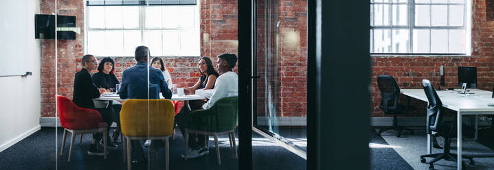 Ein Team von Geschäftsleuten bei einer Besprechung. Eine Gruppe von kreativen Geschäftsleuten bei der morgendlichen Besprechung in einem Büro. Geschäftsleute, die als Team zusammenarbeiten. - JLPSF07974