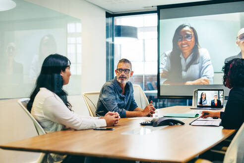 Geschäftsleute bei einer virtuellen Besprechung in einem Sitzungssaal. Eine Gruppe kreativer Geschäftsleute bei einem Briefing an einem modernen Arbeitsplatz. Ein Team globaler Geschäftsleute bei der Kommunikation mit ihren Partnern. - JLPSF08076