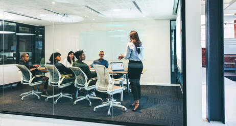 Smart businesswoman giving a financial presentation in a boardroom. Confident businesswoman presenting statistical details to her colleagues. Group of creative businesspeople attending a briefing. - JLPSF08086