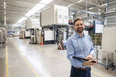 Lächelnder Geschäftsmann mit Tablet-PC in der Industrie stehend - JOSEF14174