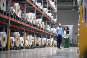 Businessman with colleague standing by rack at warehouse - JOSEF14186