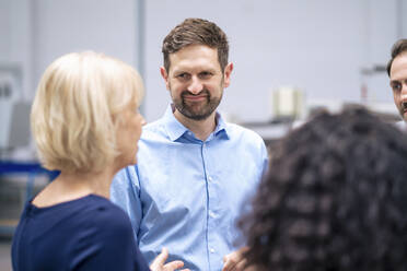 Smiling businessman with colleague discussing in factory - JOSEF14222