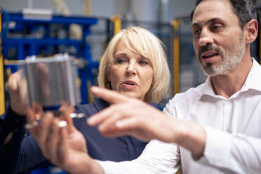 Businessman and businesswoman analyzing heating module in industry - JOSEF14289