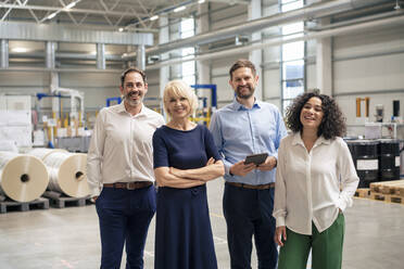 Happy business colleagues standing in industry - JOSEF14316