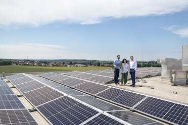 Geschäftsmann mit Laptop und Kollegen vor einem Solarpanel - JOSEF14322