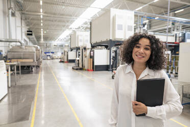 Lächelnde Geschäftsfrau mit Laptop in der Industrie - JOSEF14359