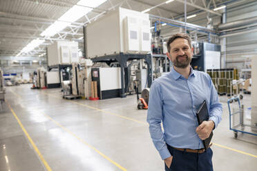 Smiling businessman holding tablet PC in factory - JOSEF14364