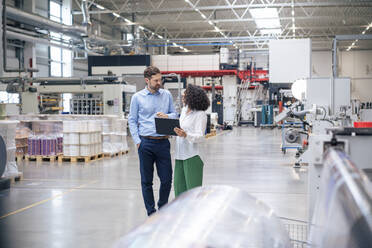 Businesswoman holding tablet PC standing by businessman in industry - JOSEF14376