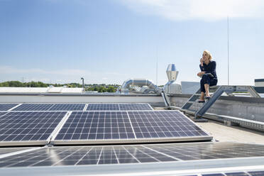 Ältere Geschäftsfrau mit Laptop vor Sonnenkollektoren auf dem Dach - JOSEF14382