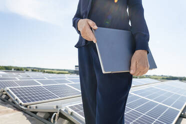 Hände einer Geschäftsfrau, die einen Laptop vor einem Sonnenkollektor hält - JOSEF14387