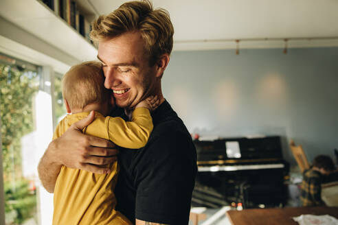 Mann im Vaterschaftsurlaub, der sich um sein neugeborenes Baby kümmert. Mann, der seinen Sohn zu Hause auf dem Arm trägt. - JLPSF08150