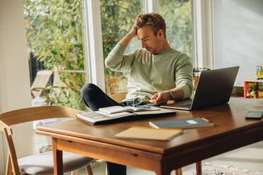 Ein Mann sieht müde aus, nachdem er lange zu Hause gearbeitet hat. Ein Geschäftsmann, der zu Hause bleibt und arbeitet, sieht gestresst aus. - JLPSF08182