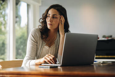 Female sitting at her work desk looking away and thinking. Stressed woman taking a break to come up with solution. - JLPSF08190