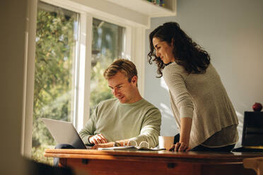 Couple looking at laptop while at home. Man working on laptop with woman looking on. - JLPSF08225