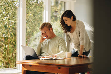 Concerned couple looking at laptop together. Man and woman at home using laptop looking serious. - JLPSF08227