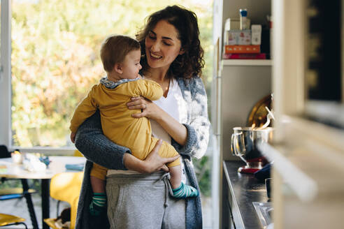 Mutter mit Baby in der Küche, Frau mit ihrem Sohn in der Küche stehend. - JLPSF08259